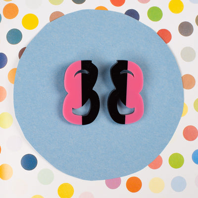 Black and Pink statement stud earrings on polka dot background