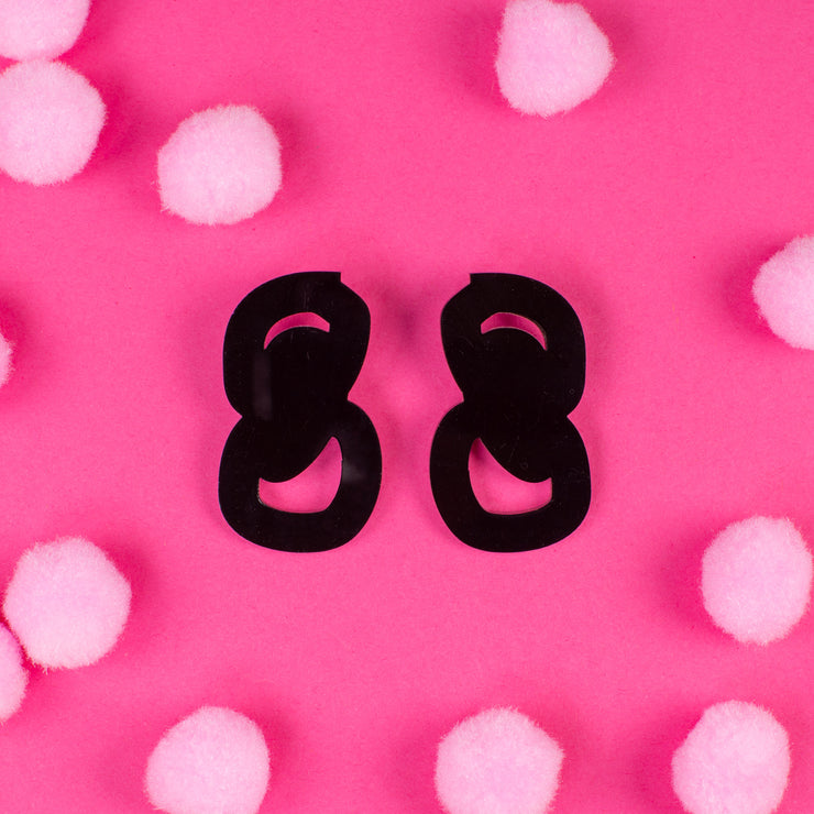 black statement stud earrings on pink background