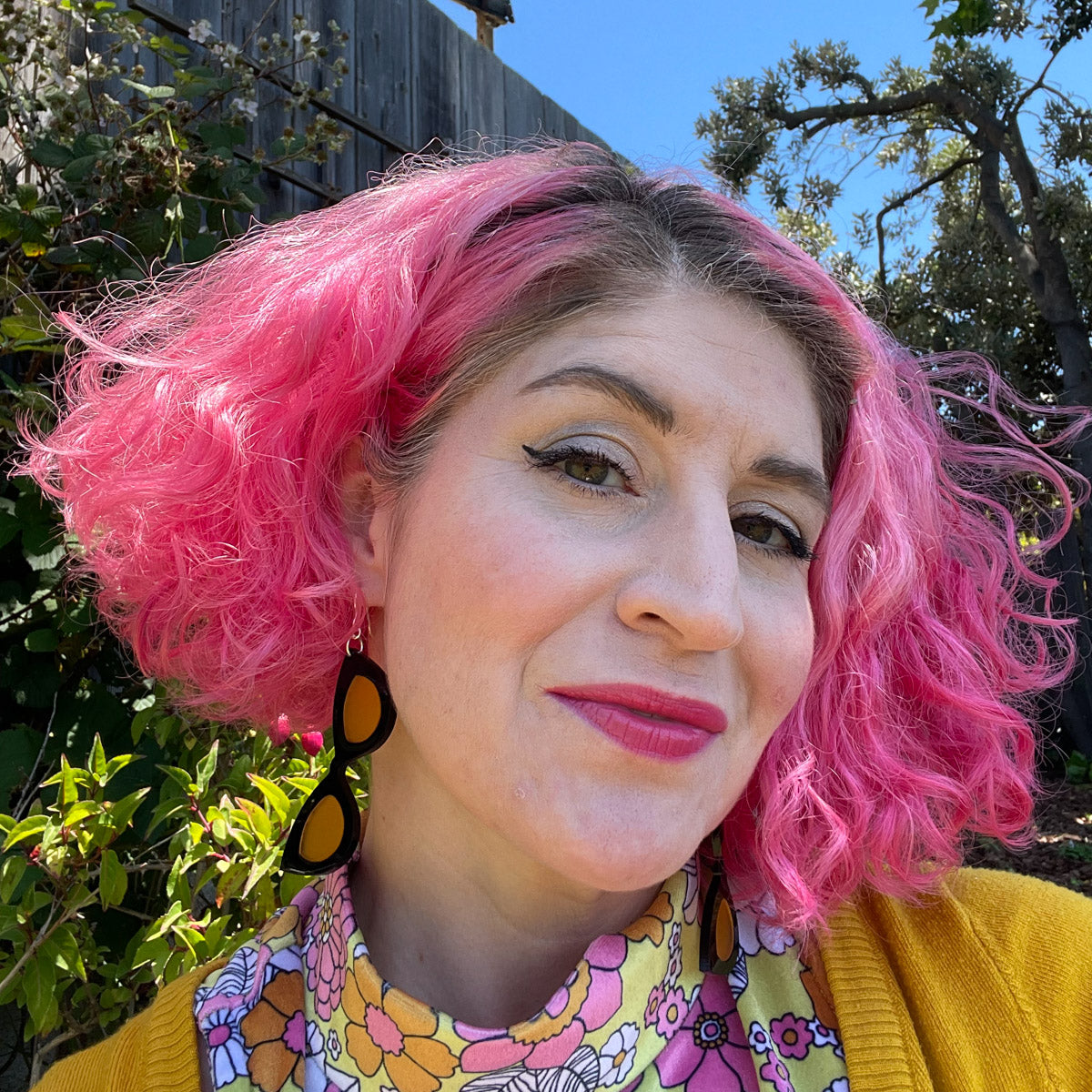 Model wearing large black and orange sunglass earrings