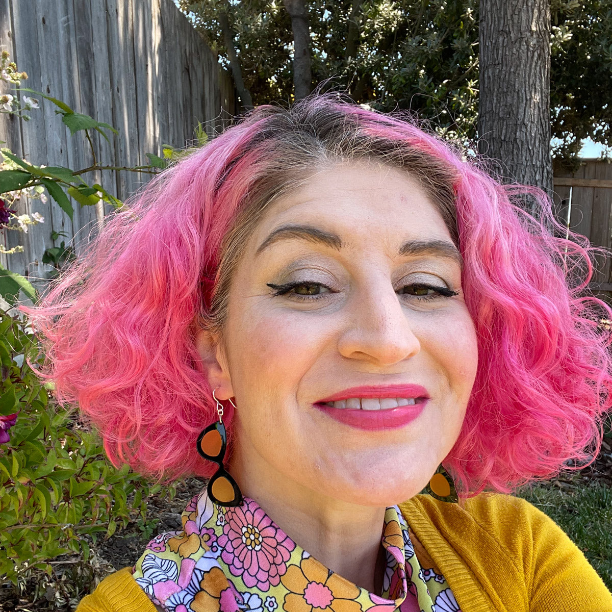 Model wearing small black and orange sunglass earrings