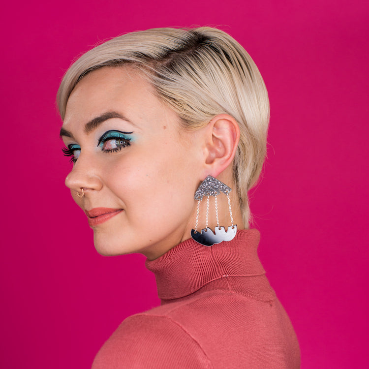 silver and black dangle earrings on model