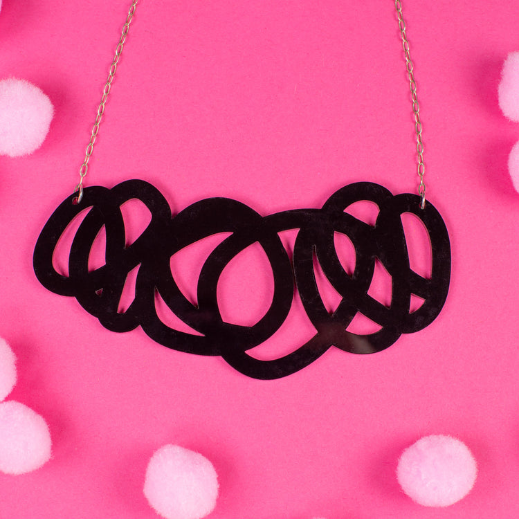 chunky black statement necklace on pink background