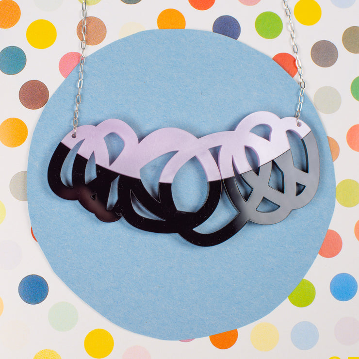 Chunky black & lilac statement necklace on polka dot background