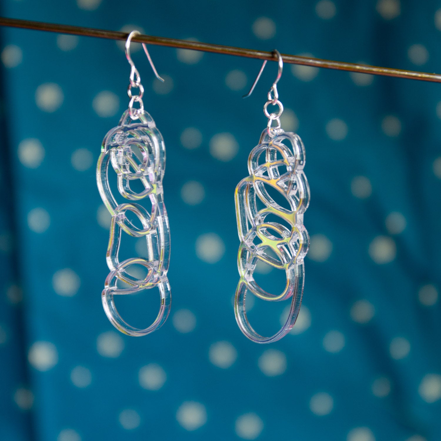 iridescent dangle earrings over blue background