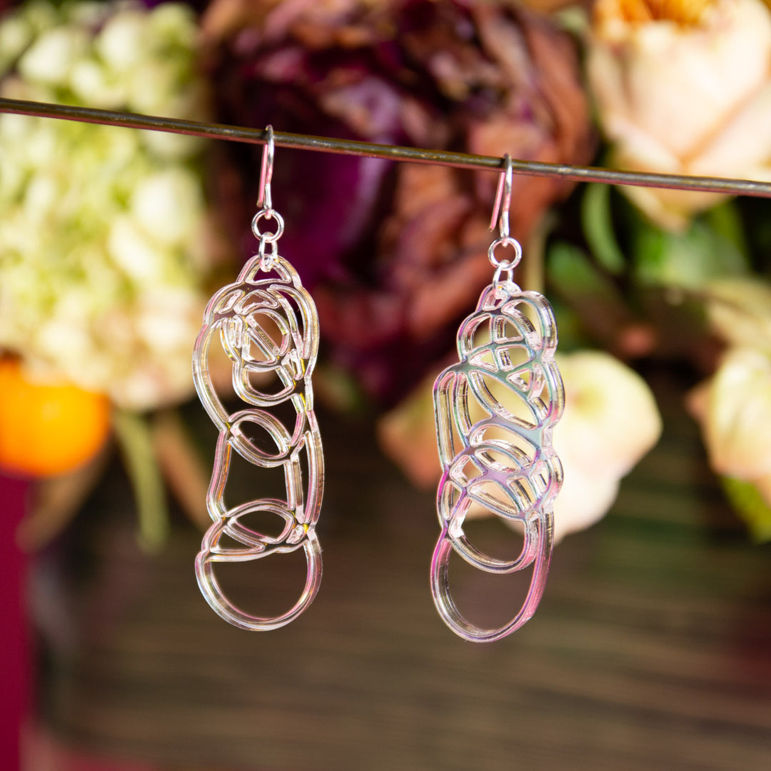 iridescent dangle earrings shown over multicolored background