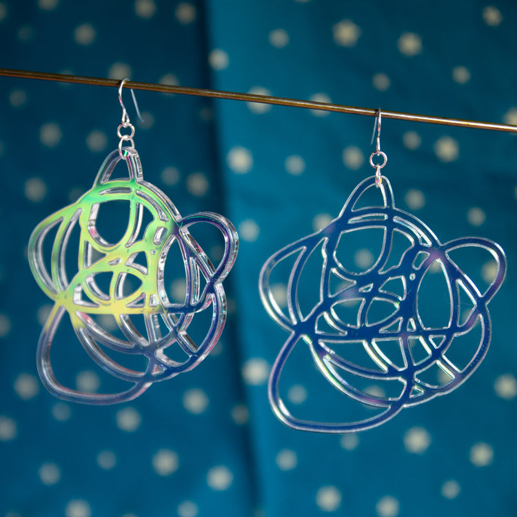 lightweight iridescent graffiti earrings in front of blue patterned backdrop