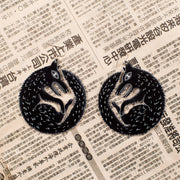 large black wolf earrings on newspaper