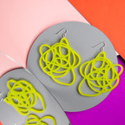 lime green statement earrings on colored background