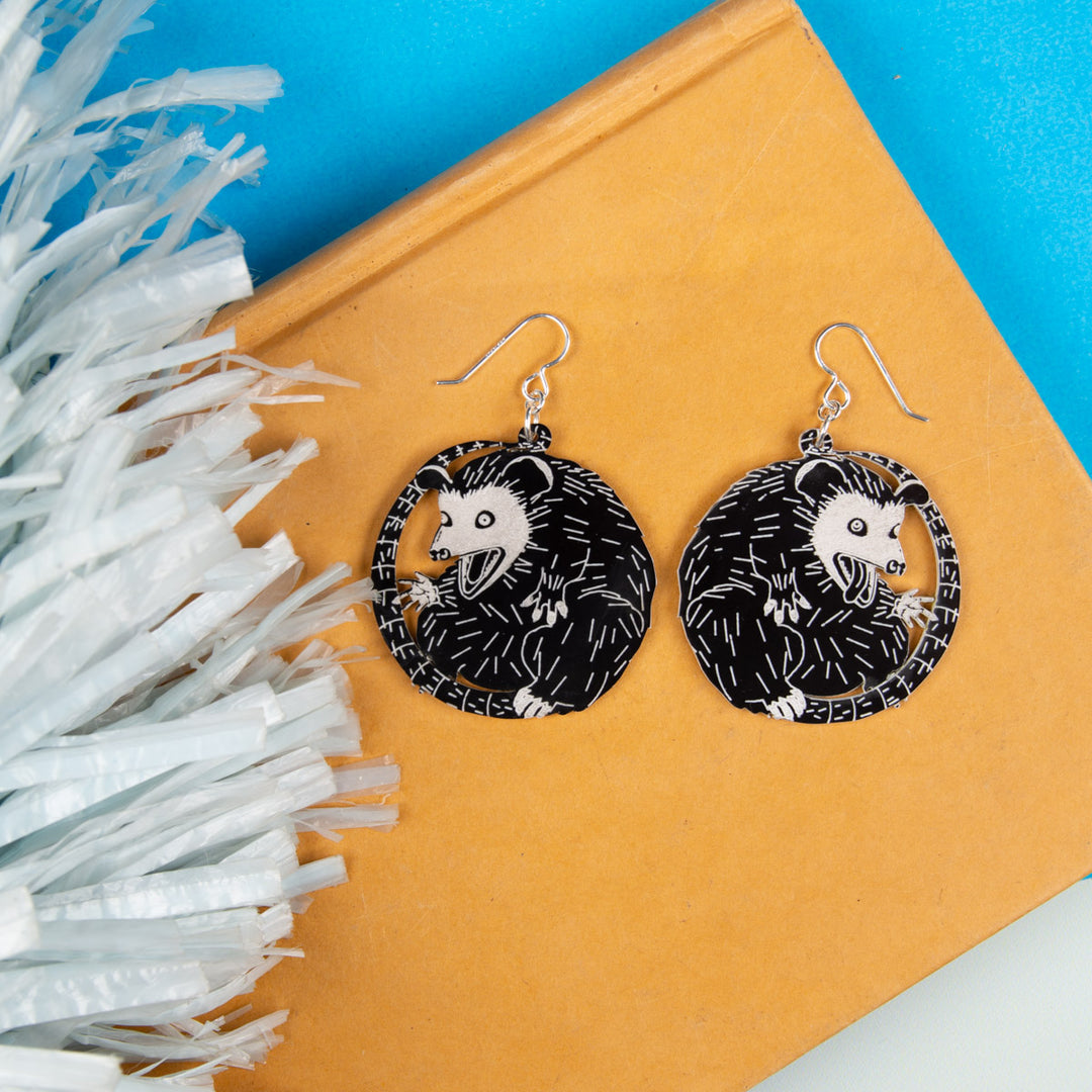 Small possum earrings on yellow book