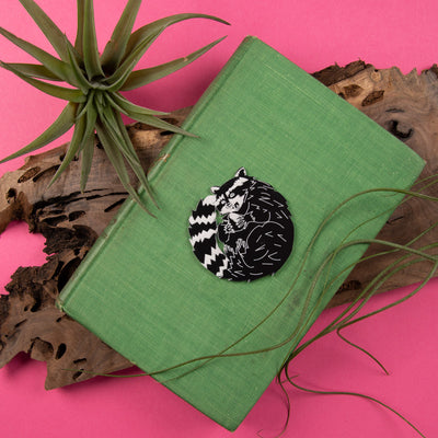 raccoon pin on green book with plants