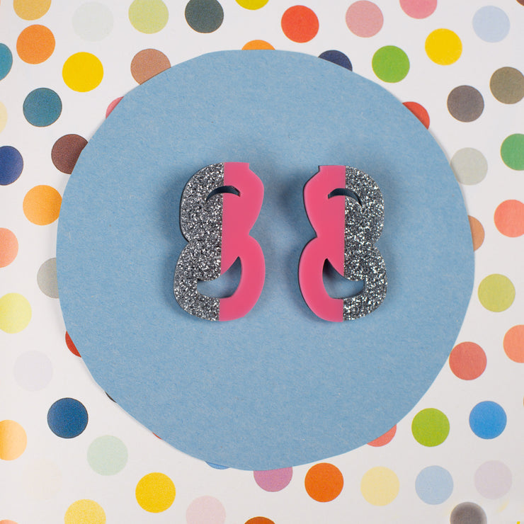 silver and pink statement stud earrings on polka dot background
