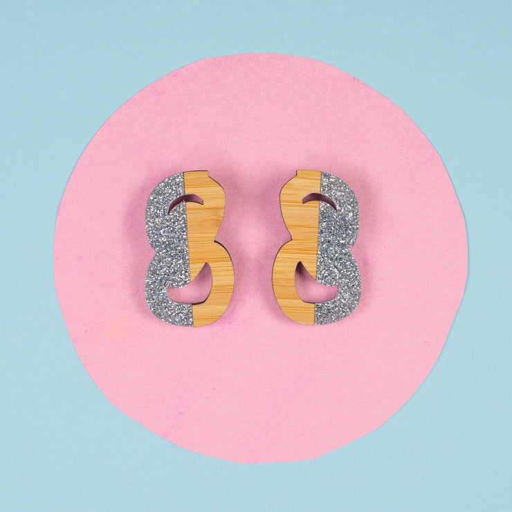 silver and wood statement studs on pink and blue background