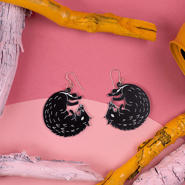 small black boar earrings styled on pink background