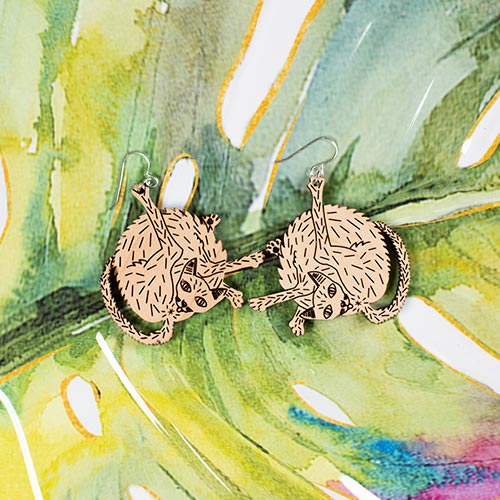 small wood cat earrings styled on colorful background