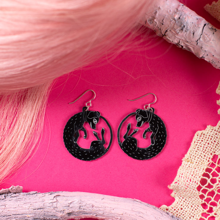 small black dog earrings on pink background