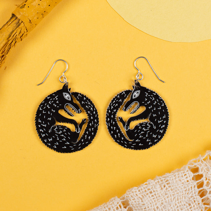 small black wolf earrings on yellow background