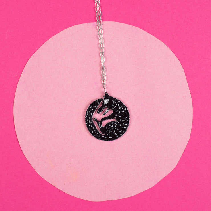 black wolf necklace on pink background