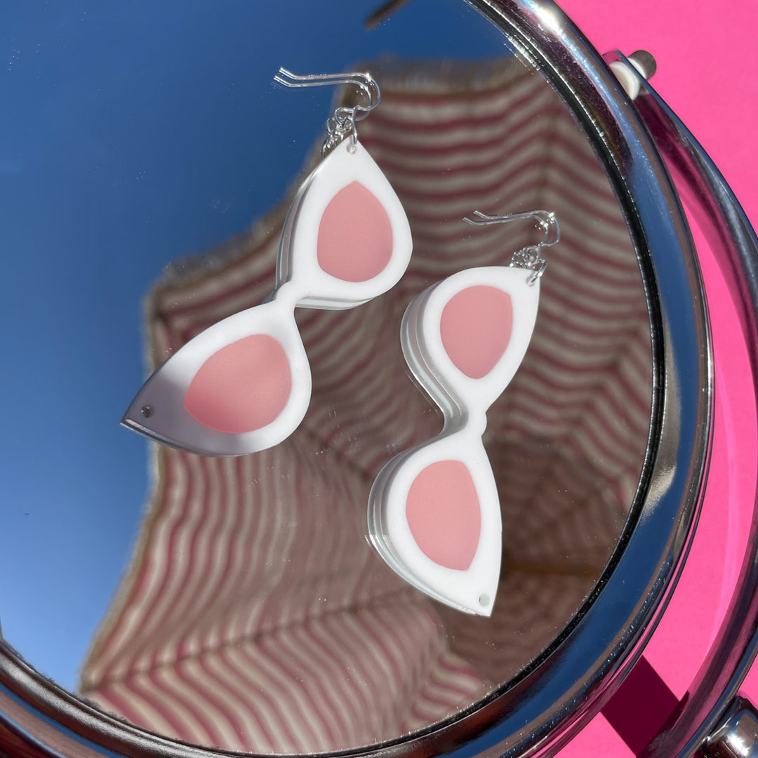 Large white sunglass earrings shown on mirror