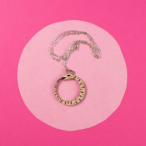 wood ouroboros necklace on pink background
