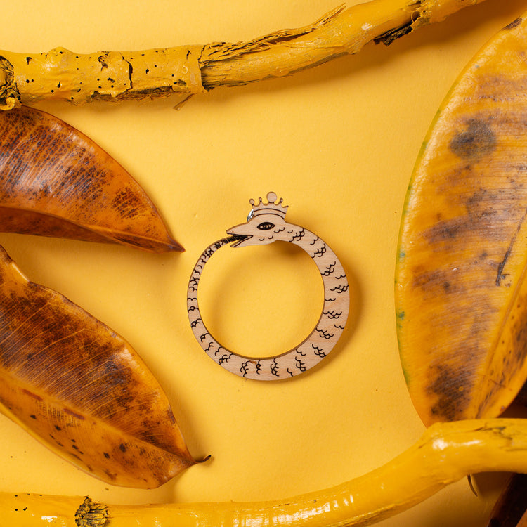 wood ouroboros pin over yellow background
